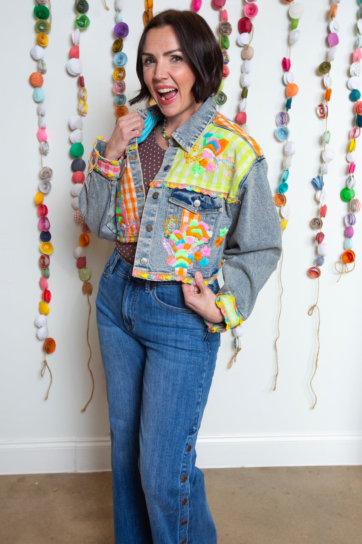 Cropped denim jacket with neon gingham patchwork and beaded embroidery worn with jeans