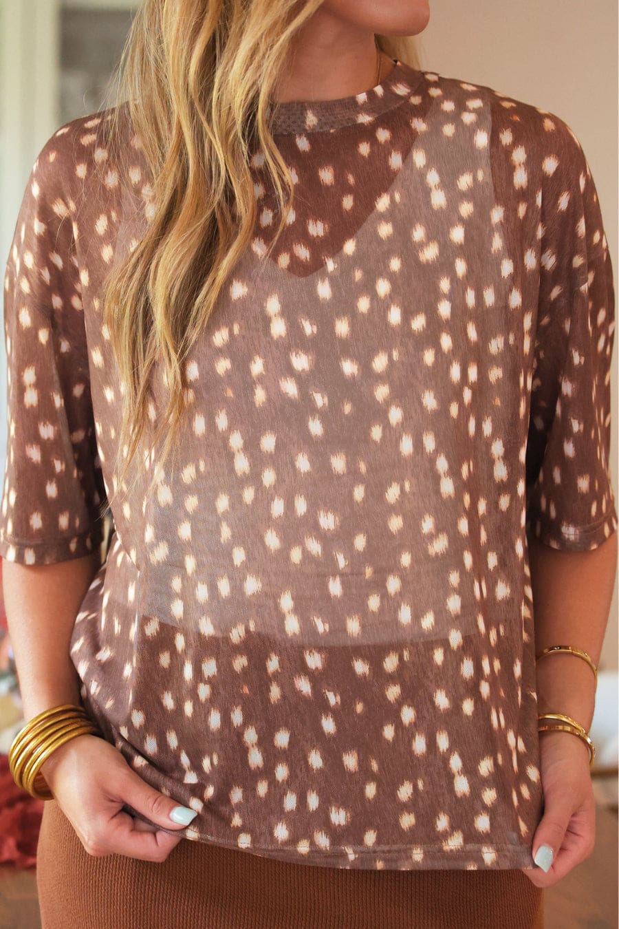 Close-up of the sheer brown mesh tee showing the cream deer spot print and elbow-length sleeves