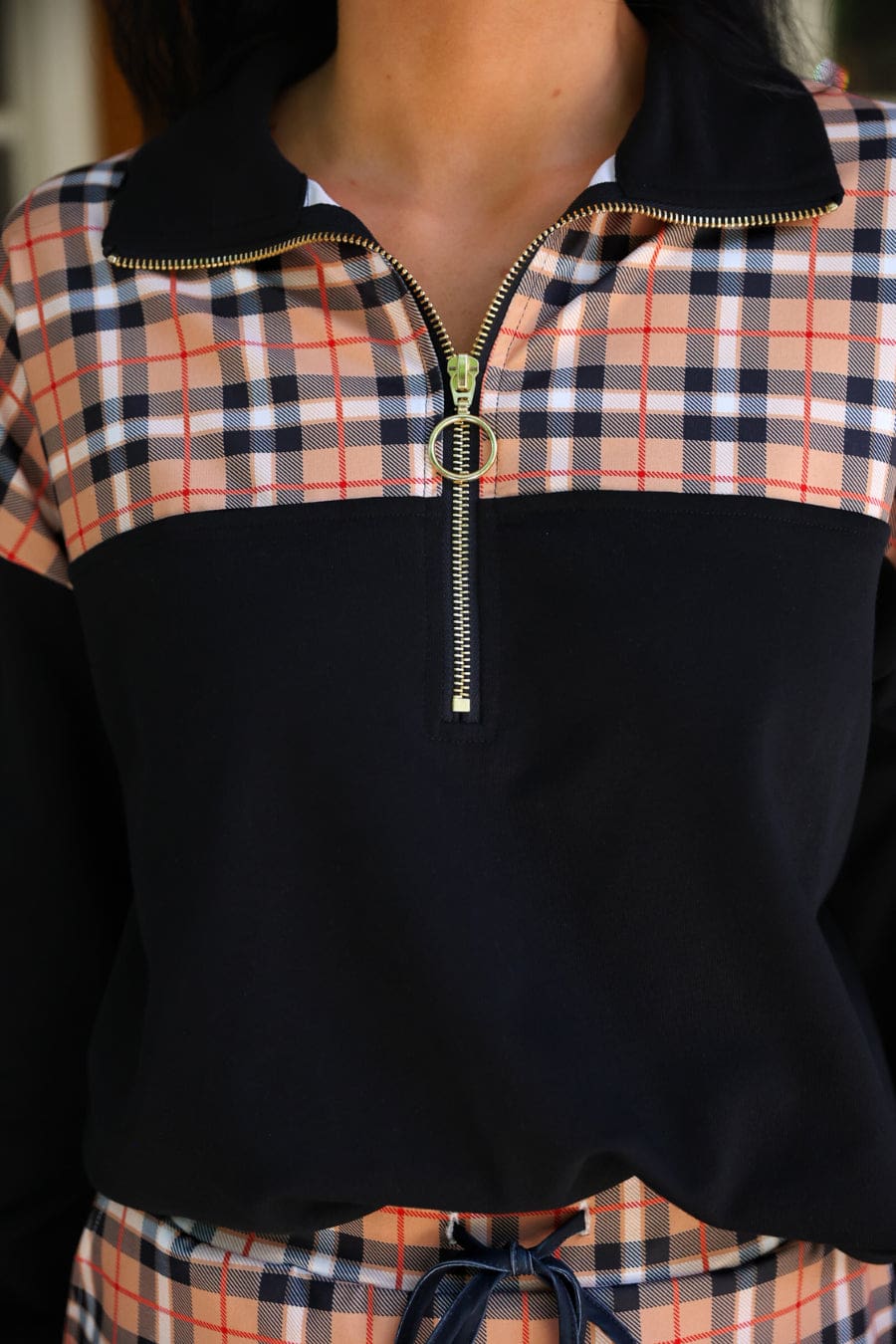 Close-up of the Nora Plaid yoke, black collar and gold ring zipper pull