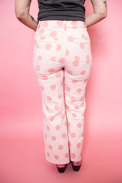 Person wearing pink polka dot pants on a pink background