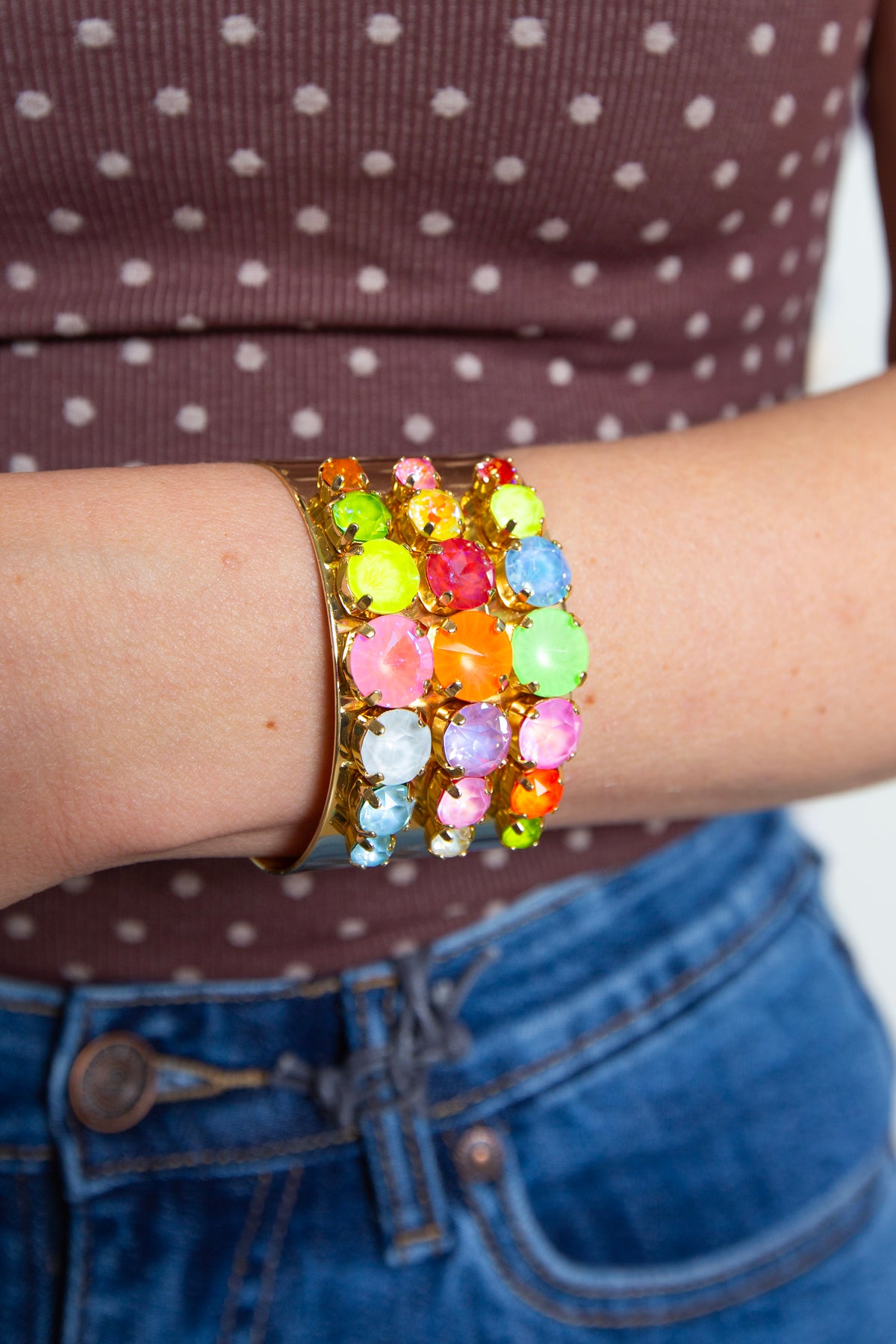 Multicolor stone cuff bracelet worn on the wrist with a polka dot top and jeans