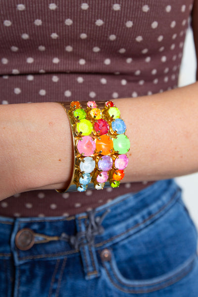 Multicolor stone cuff bracelet worn on the wrist with a polka dot top and jeans