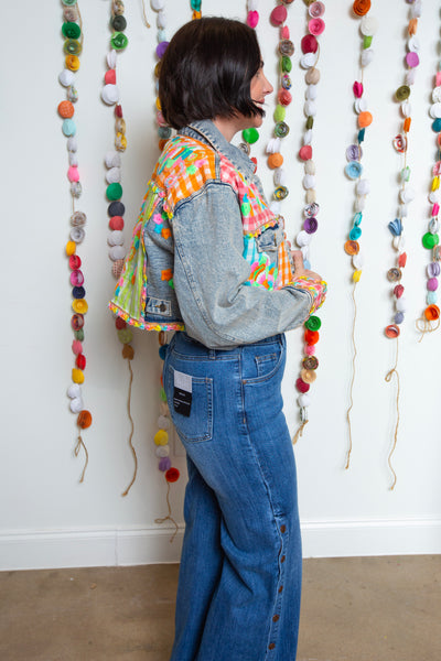 Side view of the cropped denim jacket with neon patchwork sleeves and back panel