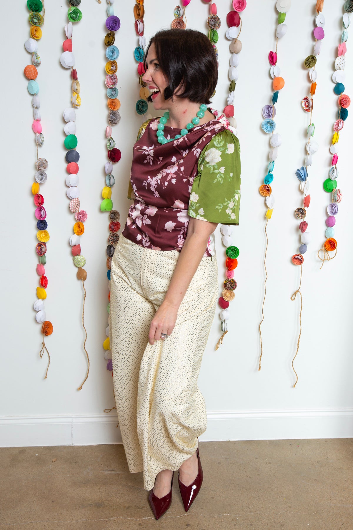 Side view of the burgundy rosette satin top with a turquoise bead necklace