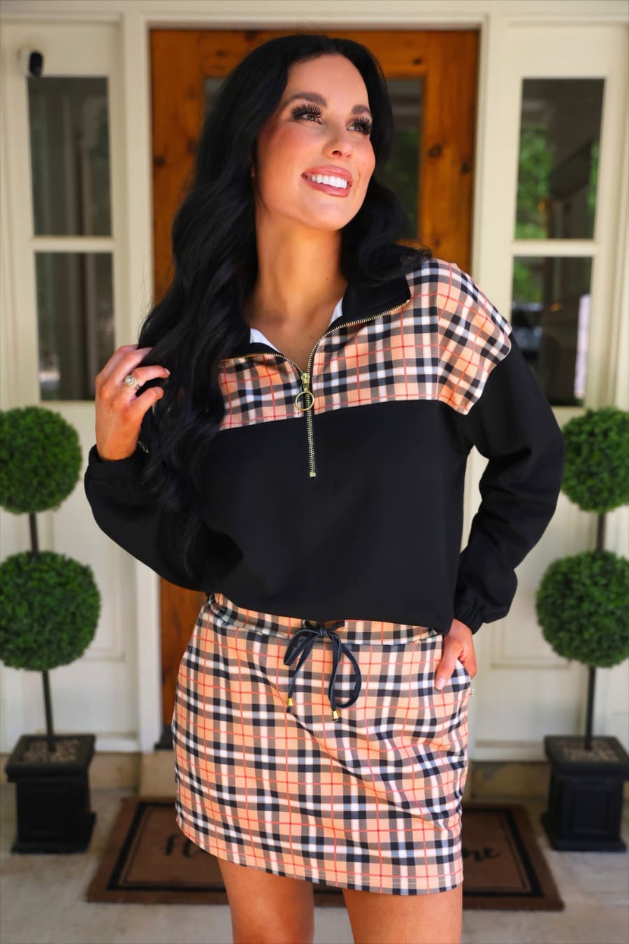 Jess Lea Mia pullover in Nora Plaid with black body and tan plaid yoke worn with a plaid skort